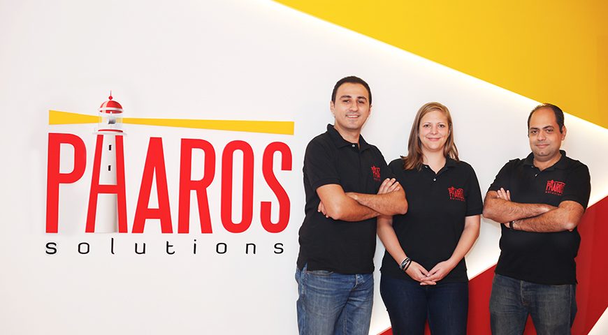 The founders of our software development company posing in front of a mural that says 'Pharos Solutions' on a wall at Egypt office